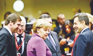 Thủ tướng Đức Angela Merkel (giữa) và Tổng thống Pháp Nicolas Sarkozy (bìa phải) vui vẻ trao đổi bên lề Hội nghị Thượng đỉnh EU hôm 9-12. Ảnh: Bloomberg