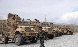 Một binh sĩ quân đội Afghanistan đi ngang qua các phương tiện chống mìn MRAP, bị bỏ lại sau khi quân đội Mỹ rời căn cứ không quân Bagram, ở tỉnh Parwan, phía bắc Kabul, Afghanistan, ngày 5 tháng 7 năm 2021. Quân Mỹ rời Sân bay Bagram của Afghanistan sau gần gần 20 năm đồn trú.