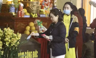 Người dân bỏ tiền công đức vào hòm khi đi lễ tại chùa Quán Sứ (quận Hoàn Kiếm, TP Hà Nội)