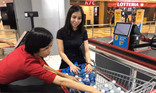Nhân viên siêu thị đang đếm các chai nước loại 1,5 lít trong xe đẩy của một khách hàng