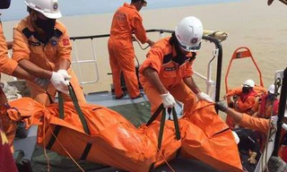 Lực lượng cứu hộ đưa thi thể một thuyền viên lên bờ.