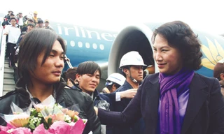 Bộ trưởng Nguyễn Thị Kim Ngân tặng hoa cho lao động sau khi xuống máy bay, sáng qua Ảnh: Đình Thắng