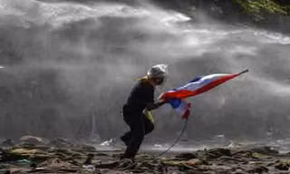 Một người bỏ chạy khi cảnh sát dùng vòi rồng trấn áp biểu tình