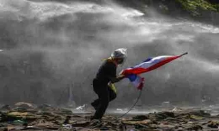 Một người bỏ chạy khi cảnh sát dùng vòi rồng trấn áp biểu tình