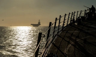 Quân nhân Mỹ trên tàu khu trục USS Bainbridge, phía xa là tàu sân bay USS Abraham Lincoln trên eo biển Gibralta ngày 13/4 ảnh: Reuters/Sputnik