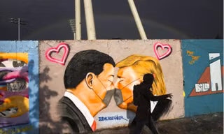 Một người đi qua bức tranh tường ở Berlin vẽ Tổng thống Mỹ Donald Trump và Chủ tịch Trung Quốc Tập Cận Bìnhảnh: AP
