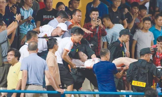 Nữ cổ động viên được đưa lên cáng đi cấp cứu sau khi bị trúng pháo sáng vào đùiảnh: VSI