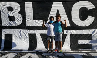 Hai cậu bé da màu đứng trước khẩu hiệu của người biểu tình căng ngoài công viên Lafayette ngày 7/6Ảnh: AP