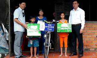 Đại diện báo Tiền Phong và Công ty Điện lực tỉnh Vĩnh Long trao quà cho em Lý Lam Chiều và em trai Lý Gia Trường.