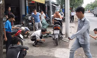 Nhiều người vây quanh xe máy để truy tìm con rắn.