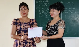 Cô Hồng Phượng (bên trái) nhận tiền hỗ trợ bữa ăn cho trò nghèo từ đại diện báo Tiền Phong