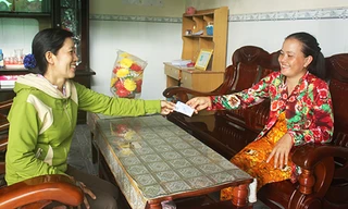 Nhân viên đại lý thu ở Hậu Giang (trái) trao thẻ BHYT cho người dân.