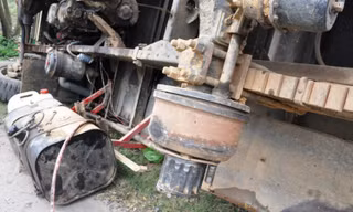 Xe tải chở gỗ tràm rơi lốp lật nhào bên đường.