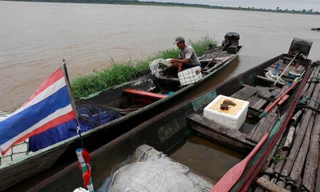 Một ngư dân Thái Lan đang múc nước khỏi thuyền đánh cá. (Ảnh: Reuters)