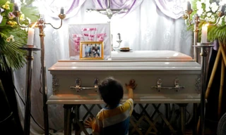 Anh trai cô bé Myka Ulpina đứng trước thi thể em gái. (Ảnh: Reuters)