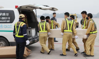 Vận chuyển các thi hài và tro cốt ra xe để đưa về địa phương. (Ảnh: TTXVN)