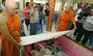  Một cặp đôi nằm trong quan tài thực hiện nghi lễ. Các nhà sư phủ vải trắng lên họ. (Nguồn: Daily Mail)