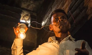 Ông Naresh ngậm dây điện trần có bóng đèn phát sáng