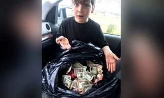 Cậu bé Griffin Steele, 7 tuổi, bên bao tiền lớn cậu tìm thấy gần thùng rác của trạm xăng.