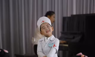 Một bé gái Triều Tiên trong trang phục y tá cười hôn nhiên.