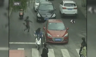 Em bé ngã sấp mặt lọt gầm chiếc xe màu trắng.