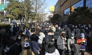 Người dân Hàn Quốc xếp hàng trước cửa hàng ở TP Daegu hôm 24/2 để chờ mua khẩu trang. Ảnh: AP