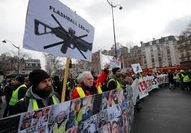 Người biểu tình 'Áo vàng' mang theo biểu ngữ phản đối, cùng ảnh của các nạn nhân bị thương khi đụng độ với cảnh sát