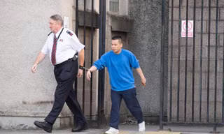 đối tượng Lê Trung Dũng đang bị cảnh sát áp tải (Ảnh: The Scottish Sun)