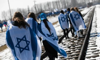 Người Israel choàng quốc kỳ lên người trong khi diễu hành trên đường ray ở trại diệt chủng Auschwitz khét tiếng của Phát xít Đức