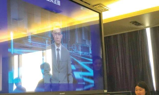 Đại diện Xinhua giới thiệu về người dẫn chương trình tin tức AI (trên màn hình) của hãng tại Bắc Kinh. Ảnh: Thái An 