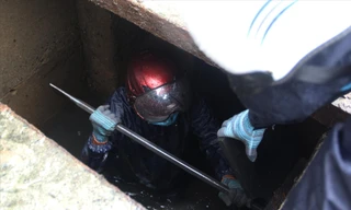 Để dọn sạch đất, rác vướng trong các ống xả, công nhân thoát nước phải ngâm mình trong nước cống liên tục. Ảnh: Giang Thanh