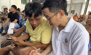 Huy Hoàng (bên phải) vận động ngư dân thay đổi nhận thức và tự giác tham gia BHYT. Ảnh THỤC HIỀN 