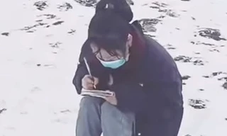 Cô nữ sinh ngồi học bài trên núi phủ đầy tuyết. (Ảnh từ clip)