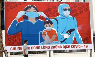 Một người đàn ông đi qua tấm áp phích kêu gọi người dân đoàn kết chống COVID-19. (Ảnh: Xinhua)