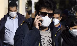 Một người đeo khẩu trang khi đang nói chuyện điện thoại ở khu trung tâm Tehran ngày 2/3. (Ảnh: AP)