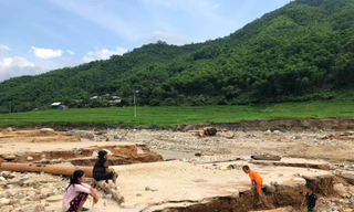 Cụ Nít cùng người thân ngồi bên nền nhà cũ bị lũ cuốn trôi, gọi tên các con đang mất tích. Ảnh: Hoàng Lam