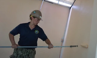 Nữ hạ sĩ quan Hải quân Hoa Kỳ Sabrina Gruett, 25 tuổi đang sơn tường một phòng học.