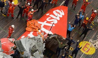 Đội trục vớt đứng cạnh phần đuôi máy bay AirAsia vừa được vớt lên, vẫy trực thăng cứu hộ