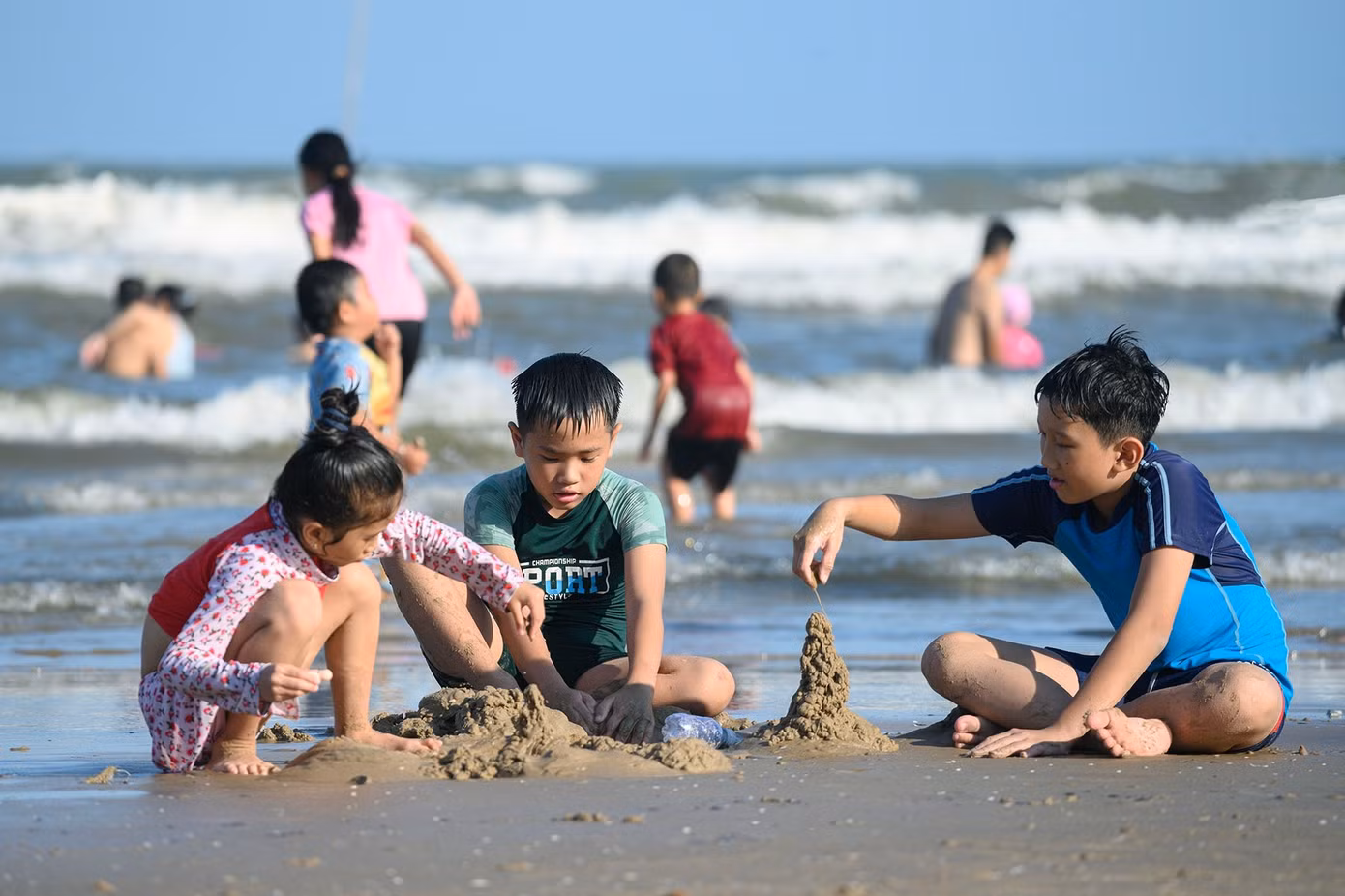 Không chỉ người lớn tắm biển, nhiều em nhỏ cũng hào hứng đào cát, xây lâu đài, chạy nhảy trên bãi biển, góp phần làm không khí thêm sôi động.