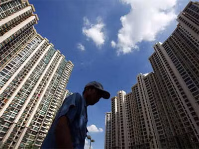 Một người lao động nghèo đi ngang qua khu nhà cao tầng ở Thượng Hải. Ảnh: China Daily