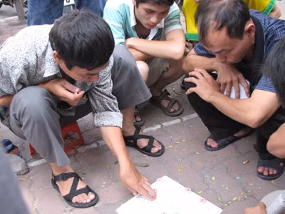 Con trong phòng thi làm bài, bố ở ngoài đánh bạc