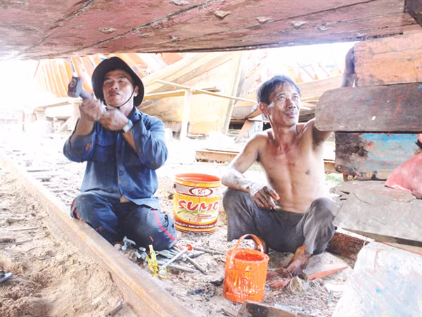 Ông Bùi Lành (phải) sửa tàu sau chuyến câu mực Trường Sa. Tàu ông chưa thể nhận hỗ trợ vì không có dấu xác nhận. Ảnh: Nguyễn Huy