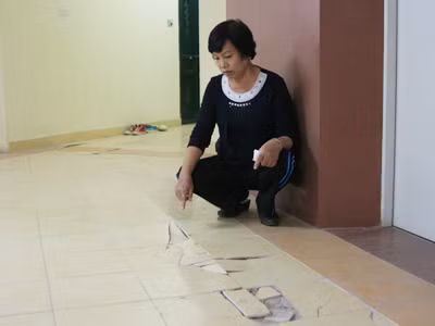 Bà Nguyễn Thị Kim, tổ phó tổ dân phố nhà B3B, ngồi trước nền nhà bị bong tróc