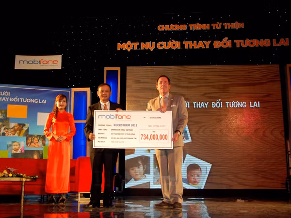 Ông Mai Văn Bình, Tổng Giám đốc MobiFone, trao 734 triệu đồng tiền bán vé Rockstorm cho ông Grey McFall, Phó Chủ tịch ban cố vấn Operation Smile Việt Nam