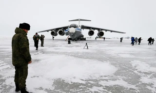 Một sĩ quan Nga đứng gần chiếc máy bay vận tải quân sự Ilyushin Il-76 đã hạ cánh trên đảo Alexandra Land gần Nagurskoye, Nga ngày 17/5/2021. Từng là vùng đất hoang vu chủ yếu có gấu Bắc Cực sinh sống, tiền đồn quân sự cực Bắc của Nga hiện được trang bị dày đặc tên lửa và radar, với đường băng mở rộng có thể tiếp nhận mọi loại máy bay, bao gồm máy bay ném bom chiến lược mang vũ khí hạt nhân, qua đó thể hiện sức mạnh và ảnh hưởng của Nga trên khắp Bắc Cực trong bối cảnh cạnh tranh quốc tế ngày càng gia tăng nhằm giành quyền kiểm soát nguồn tài nguyên khổng lồ tại khu vực này. Ảnh: AP.