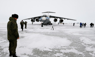 Một sĩ quan Nga đứng gần chiếc máy bay vận tải quân sự Ilyushin Il-76 đã hạ cánh trên đảo Alexandra Land gần Nagurskoye, Nga ngày 17/5/2021. Từng là vùng đất hoang vu chủ yếu có gấu Bắc Cực sinh sống, tiền đồn quân sự cực Bắc của Nga hiện được trang bị dày đặc tên lửa và radar, với đường băng mở rộng có thể tiếp nhận mọi loại máy bay, bao gồm máy bay ném bom chiến lược mang vũ khí hạt nhân, qua đó thể hiện sức mạnh và ảnh hưởng của Nga trên khắp Bắc Cực trong bối cảnh cạnh tranh quốc tế ngày càng gia tăng nhằm giành quyền kiểm soát nguồn tài nguyên khổng lồ tại khu vực này. Ảnh: AP.