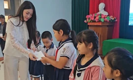 Người đẹp Phùng Thị Hương Giang trao quà cho các em học sinh bị ảnh hưởng bởi lũ lụt.