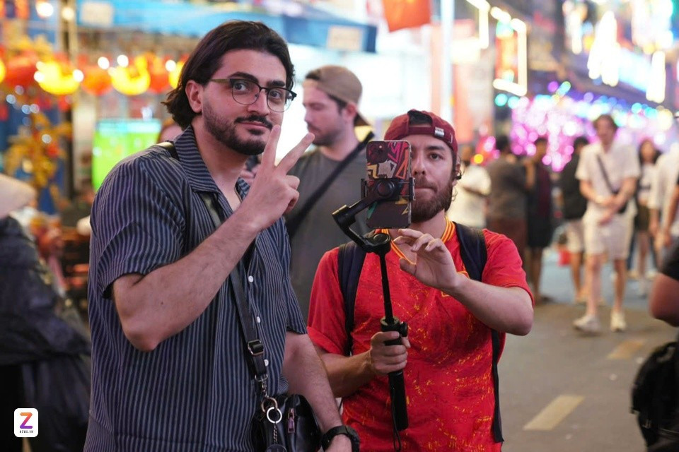 Du khách Mos (áo đỏ, đến từ Azerbaijan) cùng bạn theo dõi trận đấu bóng đá tại phố Tây Bùi Viện (TP.HCM) tối 21/1. Ảnh: Linh Huỳnh.