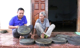 Nghệ nhân Y Krai Cil (phải) giới thiệu về bộ chiêng quý của gia đình 