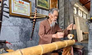 Cụ Chu Văn Thim chơi đàn bầu tự làm bằng ống bương tại đền Thái Vi Ảnh: Đình Minh 